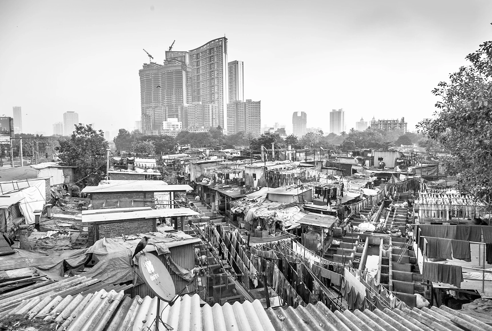 Vista panorámica del Dhobi Ghat de Mumbai en blanco y negro, lavanderos entre tinas y rascacielos al fondo — Dobhi Wallahs, Cristina Riesgo